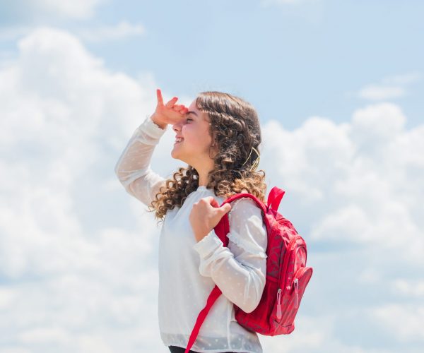 small kid on sunny sky background. summer and spring season. holiday and vacation. happy childhood. smiling student with school bag. back to school. little girl carry backpack. Preparing to exams.